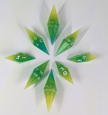A complete set of diamond shaped resin dice featuring 2 d20s. These handmade dice are yellow and teal swirls with white numbers and are clustered in a circle with the bottom points angled toward a central point on a white background.