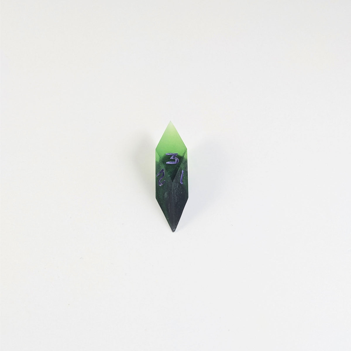 A mid angle view of a diamond d3 with swirls of black and green with purple numbers that glow in the dark on a white background.