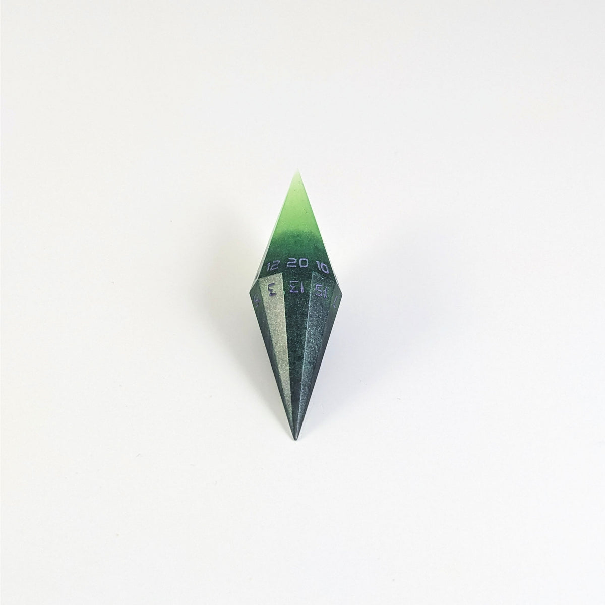 A mid angle view of a diamond d20 with swirls of black and green with purple numbers that glow in the dark on a white background.