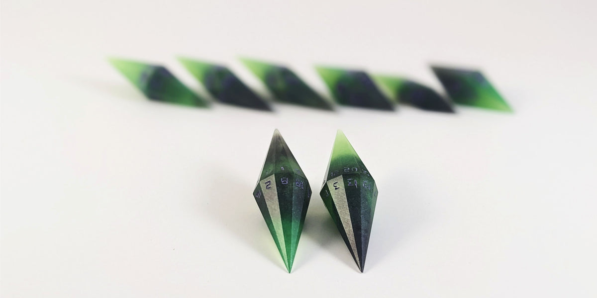 A straight on photo of a diamond set of DnD dice that are black and green with purple numbers that glow in the dark focusing on 2 d20s in the center. The d20 on the left has the 1 face up and the d20 on the right has the 20 face up. The other 6 dice are lined up in the background but are out of focus, while the d20s are in sharp focus.