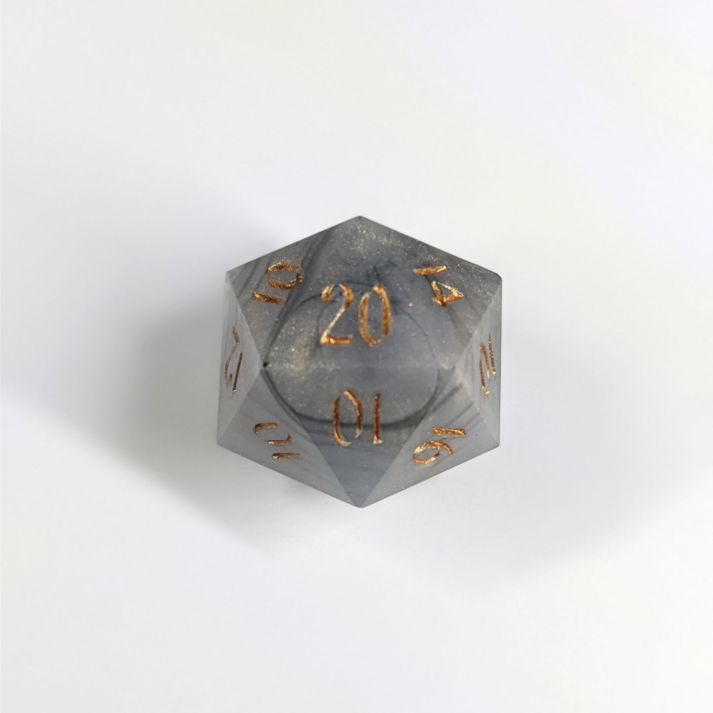 A top down photo of a reliable talent d20 on a white background. The die is black and white marbled with a slight gold shimmer and gold numbers. Faces that would be 9 or below are replaced with a 10.