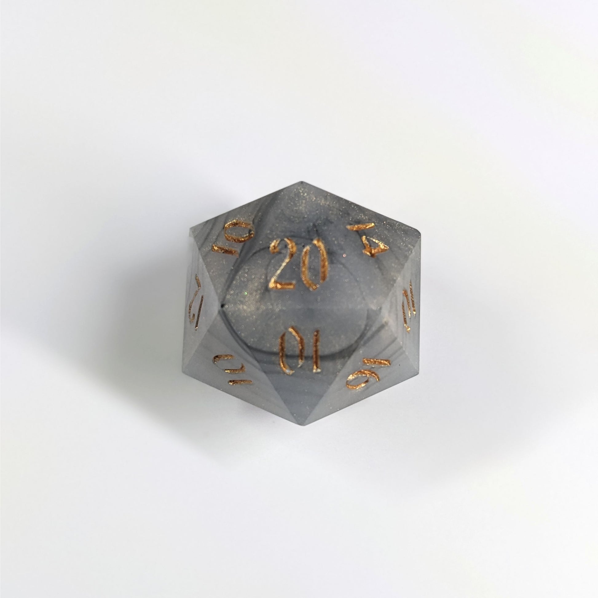 A top down photo of a reliable talent d20 on a white background. The die is black and white marbled with a slight gold shimmer and gold numbers. Faces that would be 9 or below are replaced with a 10.