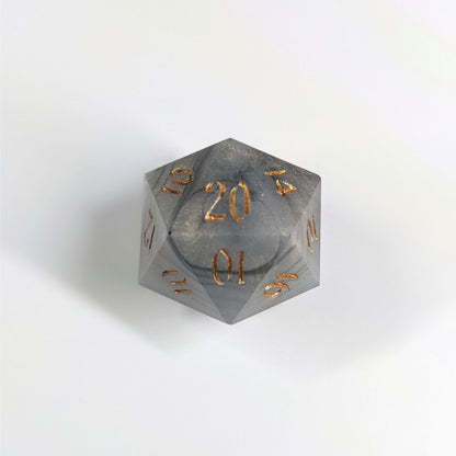 A top down photo of a reliable talent d20 on a white background. The die is black and white marbled with a slight gold shimmer and gold numbers. Faces that would be 9 or below are replaced with a 10.