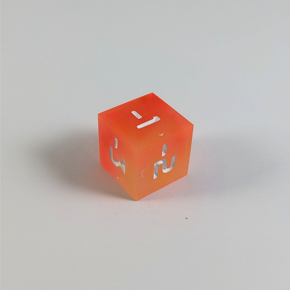 A mid angle photo of an orange negative spindown d6 with white numbers sits on a white background with the corner of the -1, -2, and -3 faces angled toward the camera.