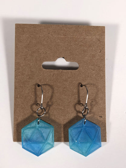 A pair of oceanic blue and green dangly, flat d20 earrings with silver color titanium and niobium hardware on a kraft earring card on a white background.