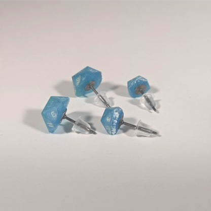 Two pairs of handmade d20 earrings that are oceanic shades of blue and green with sandy white numbers turned to show the titanium hardware and bell shaped rubber backs.