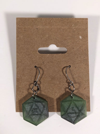 A pair of dark green and dark silver dangly, flat d20 earrings with silver color titanium and niobium hardware on a kraft earring card on a white background. The earring on the left has a 20 on it and the earring on the right has a 1 on it, both in a sci-fi style font.