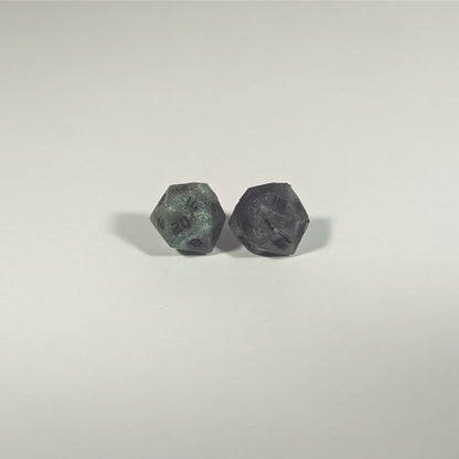 A single pair of the larger size handmade d20 earrings with titanium hardware that are green and dark silver with black numbers on a white background. The earring on the left centers the 20 face and the earring on the right centers the 1 face.