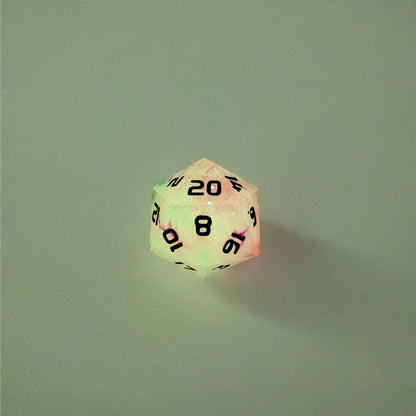 A high angle photo of a standard d20 glowing slightly green with pink/purple swirls and black numbers with the 20 face up on a white background.