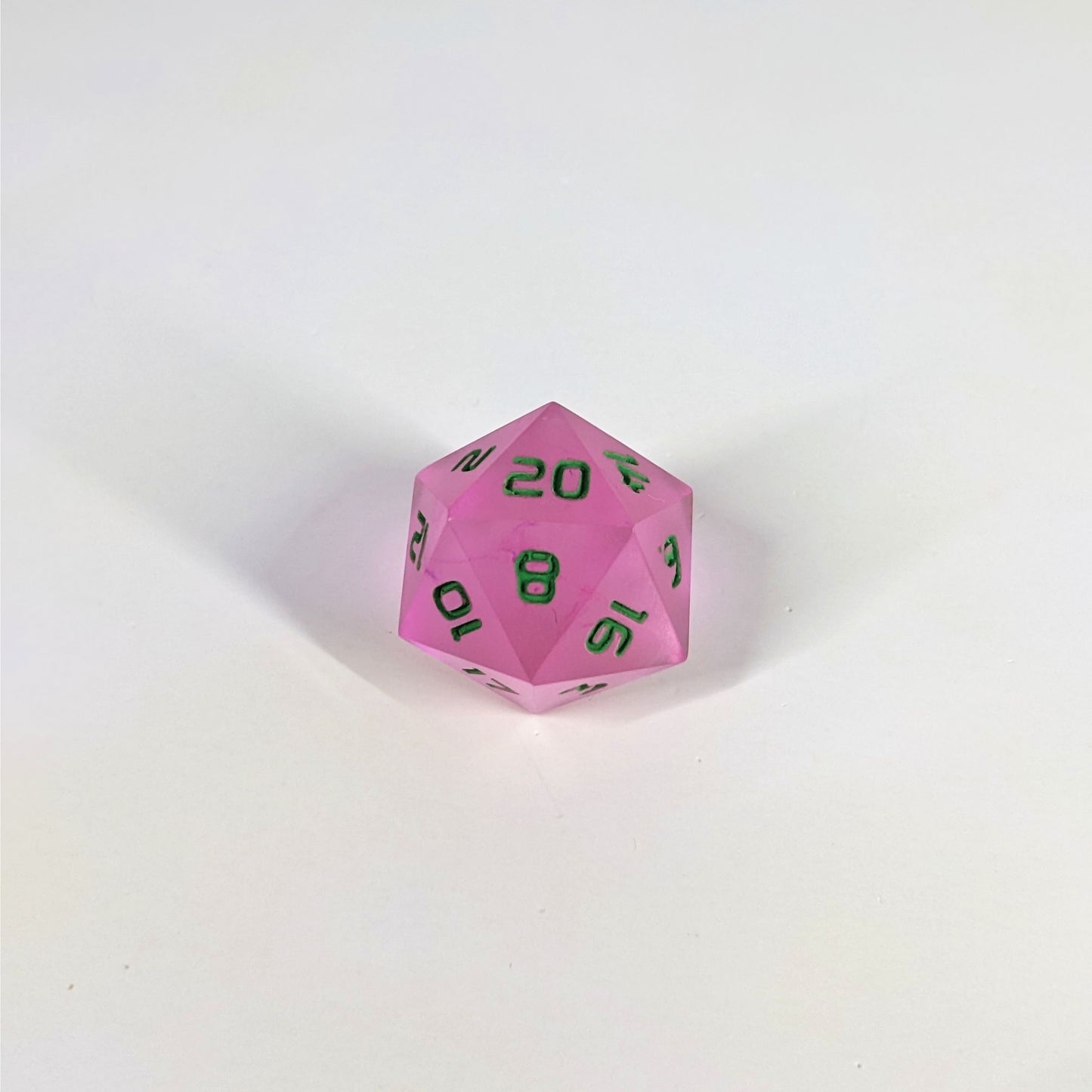 A high angle photo of a standard d20 with pink/purple swirls and green numbers with the 20 face up on a white background.