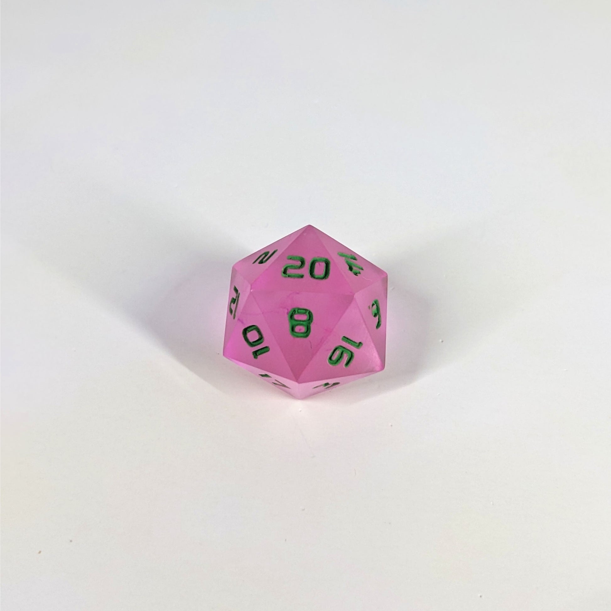A high angle photo of a standard d20 with pink/purple swirls and green numbers with the 20 face up on a white background.
