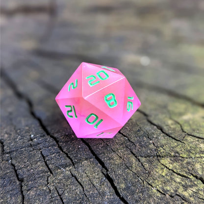 A standard d20 with pink/purple swirls and green numbers sits on a wood stump with the 20 face up.