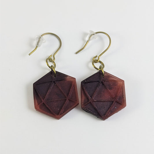 A pair of maroon and red dangly, flat d20 earrings with gold color titanium and niobium hardware and bell shaped rubber backs on a white background.