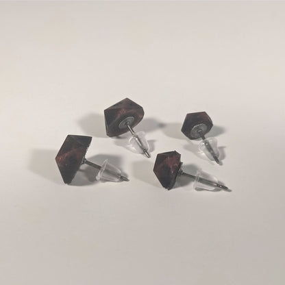 Two pairs of handmade d20 earrings that are swirls of red with black numbers turned to show the titanium hardware and bell shaped rubber backs.