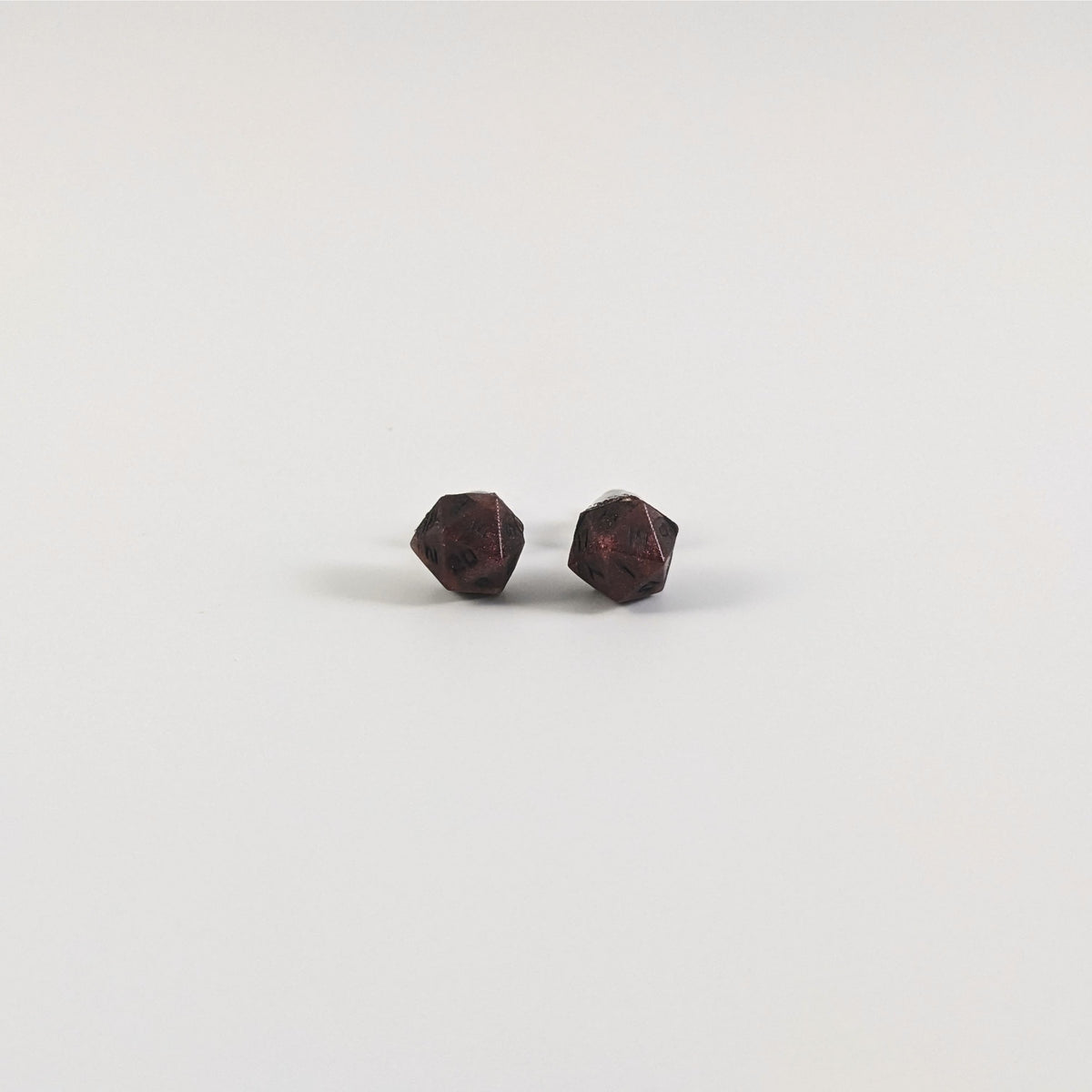 A single pair of the smaller size handmade d20 earrings with titanium hardware that are swirls of red with black numbers on a white background. The earring on the left centers the 20 face and the earring on the right centers the 1 face.