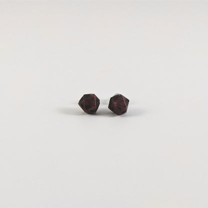 A single pair of the smaller size handmade d20 earrings with titanium hardware that are swirls of red with black numbers on a white background. The earring on the left centers the 20 face and the earring on the right centers the 1 face.