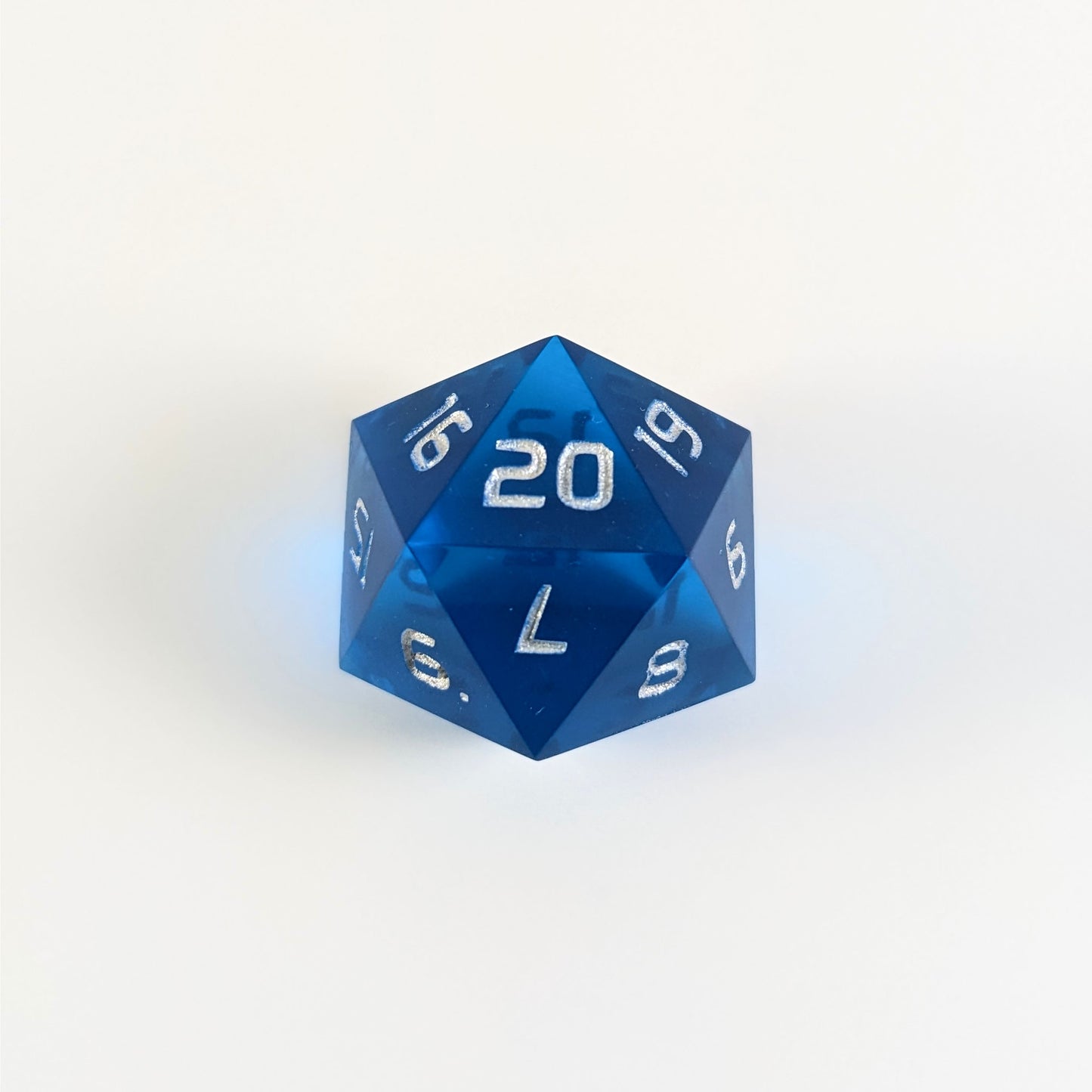 A blue spindown d20 with silver numbers and a right spin sits on a white background with the 20 face up.