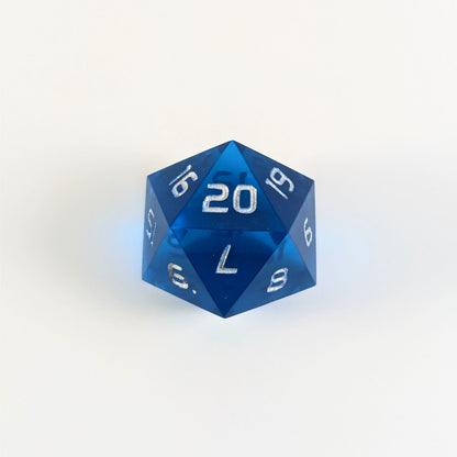 A blue spindown d20 with silver numbers and a right spin sits on a white background with the 20 face up.