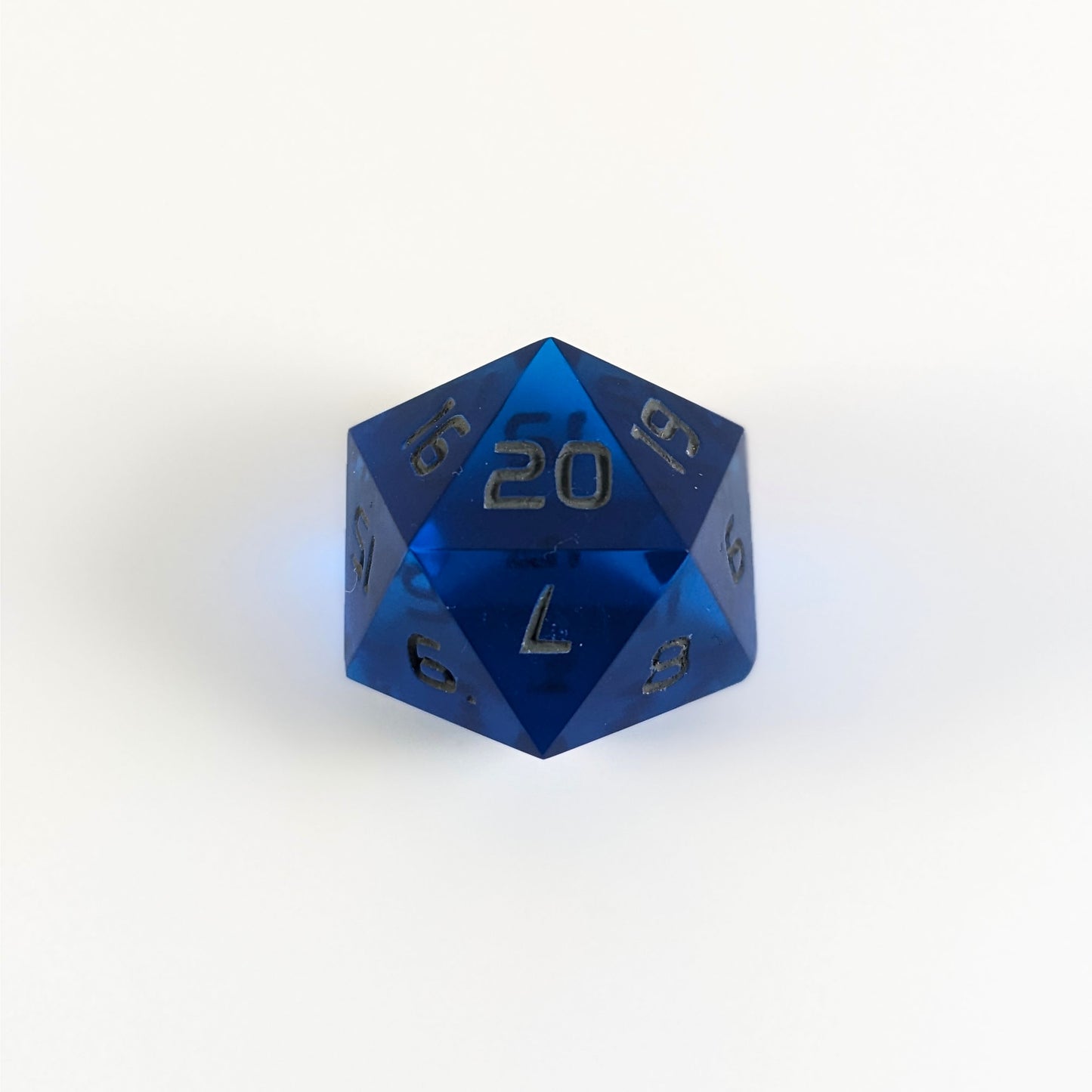 A blue spindown d20 with gray numbers and a right spin sits on a white background with the 20 face up.