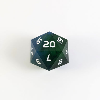 A blue and green spindown d20 with white numbers and a right spin sits on a white background with the 20 face up.
