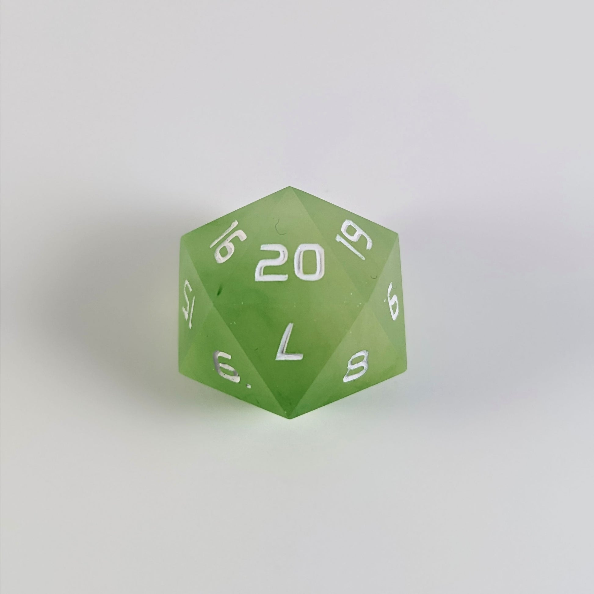 A yellow green spindown d20 with white numbers and a right spin sits on a white background with the 20 face up.