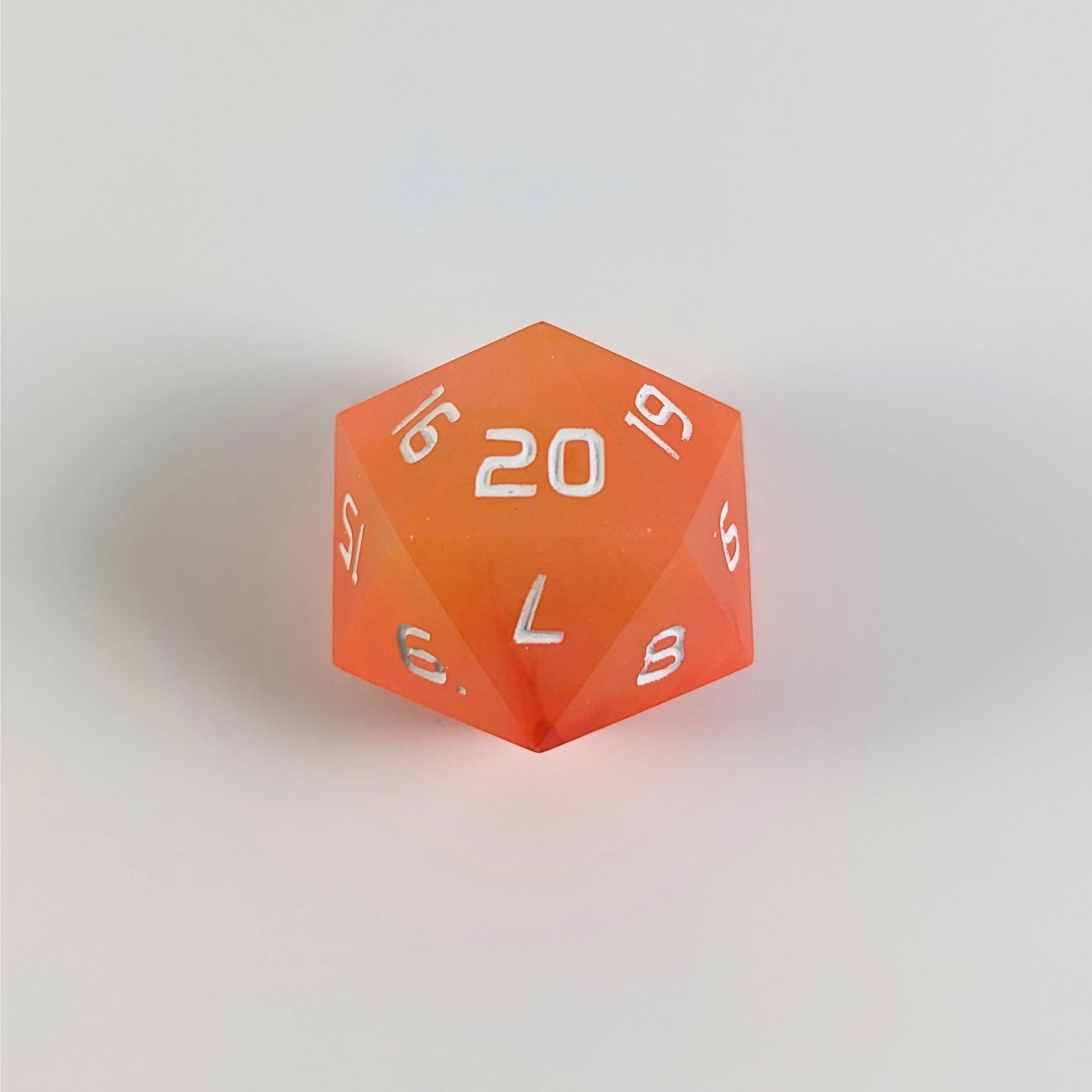 An orange spindown d20 with white numbers and a right spin sits on a white background with the 20 face up.