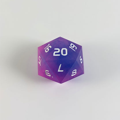 A pink and blue spindown d20 with white numbers and a right spin sits on a white background with the 20 face up.