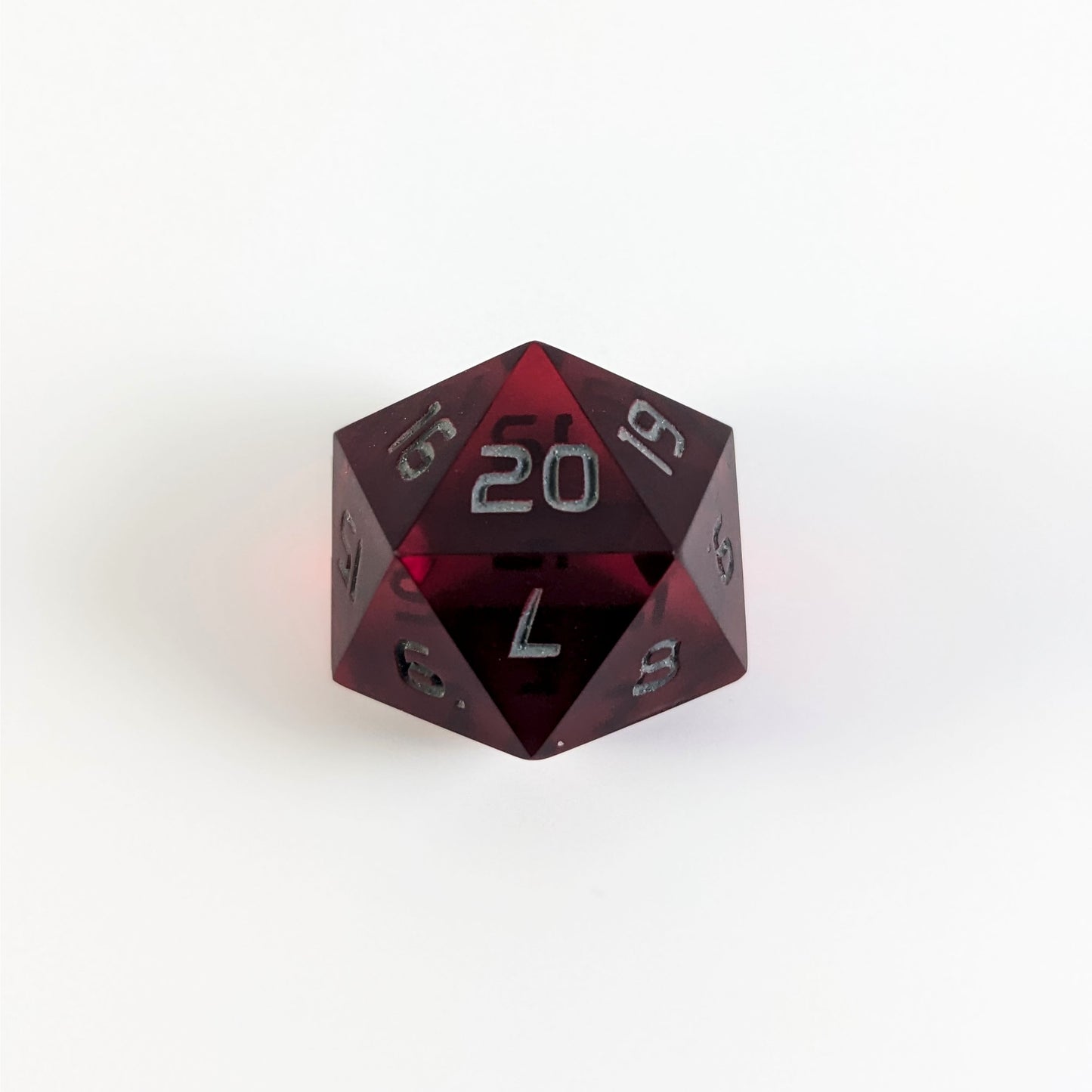 A red spindown d20 with gray numbers and a right spin sits on a white background with the 20 face up.
