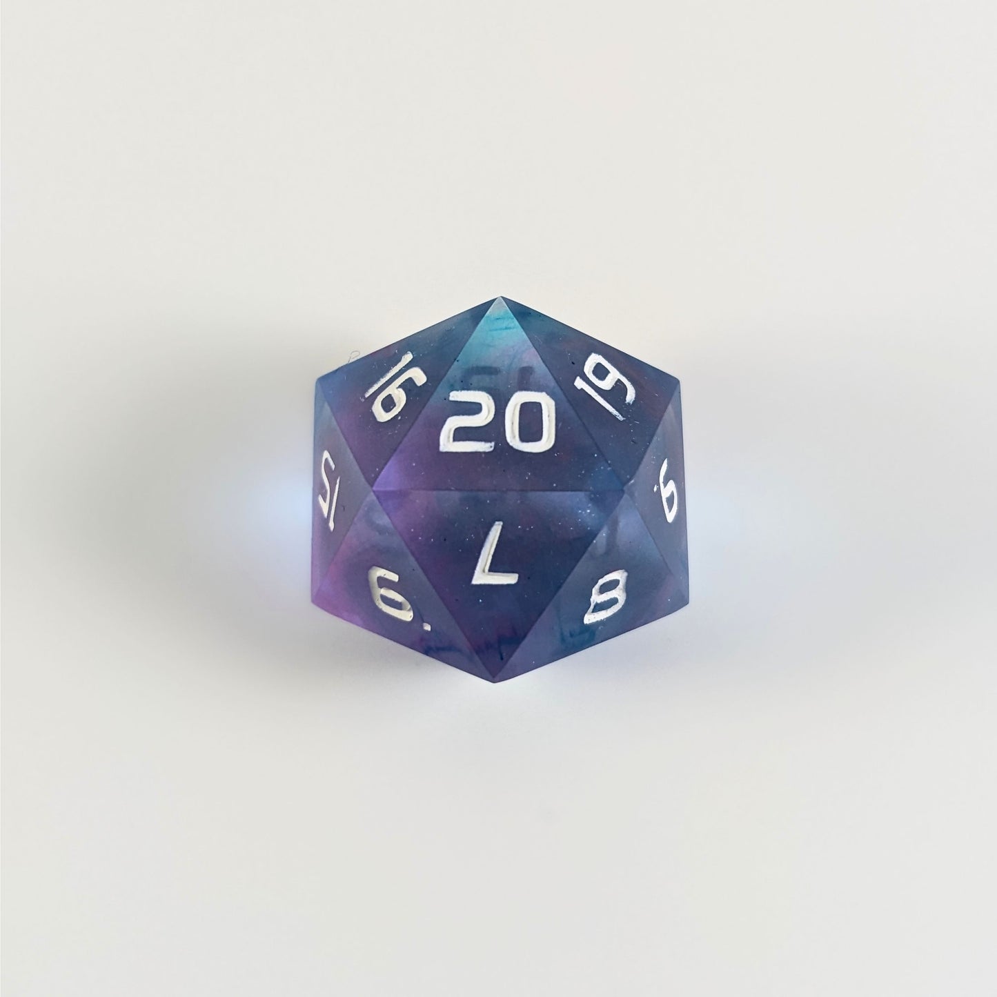 A clear pink and teal spindown d20 with white numbers and a right spin sits on a white background with the 20 face up.