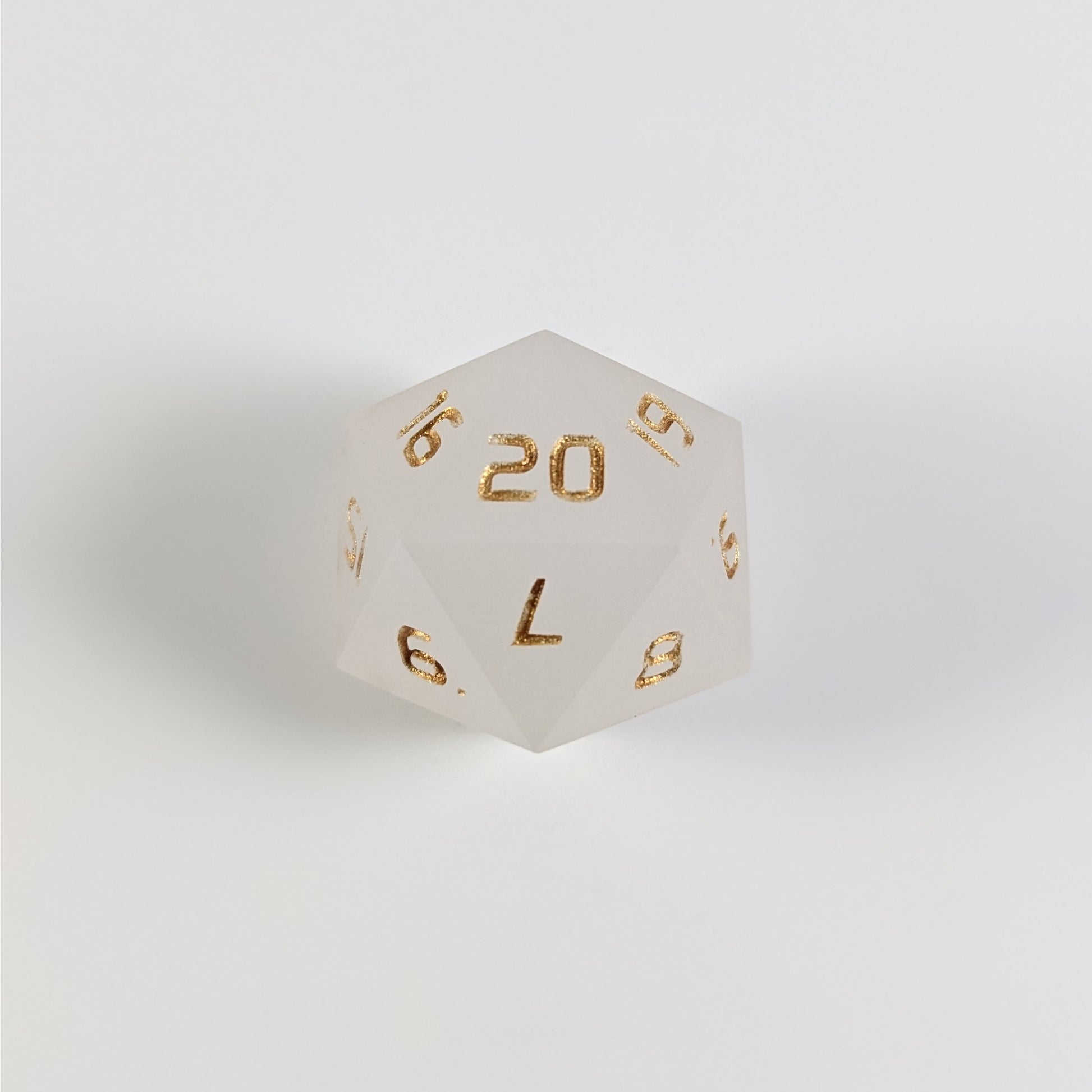 A white spindown d20 with gold numbers and a right spin sits on a white background with the 20 face up.