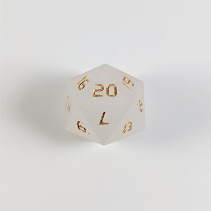 A white spindown d20 with gold numbers and a right spin sits on a white background with the 20 face up.