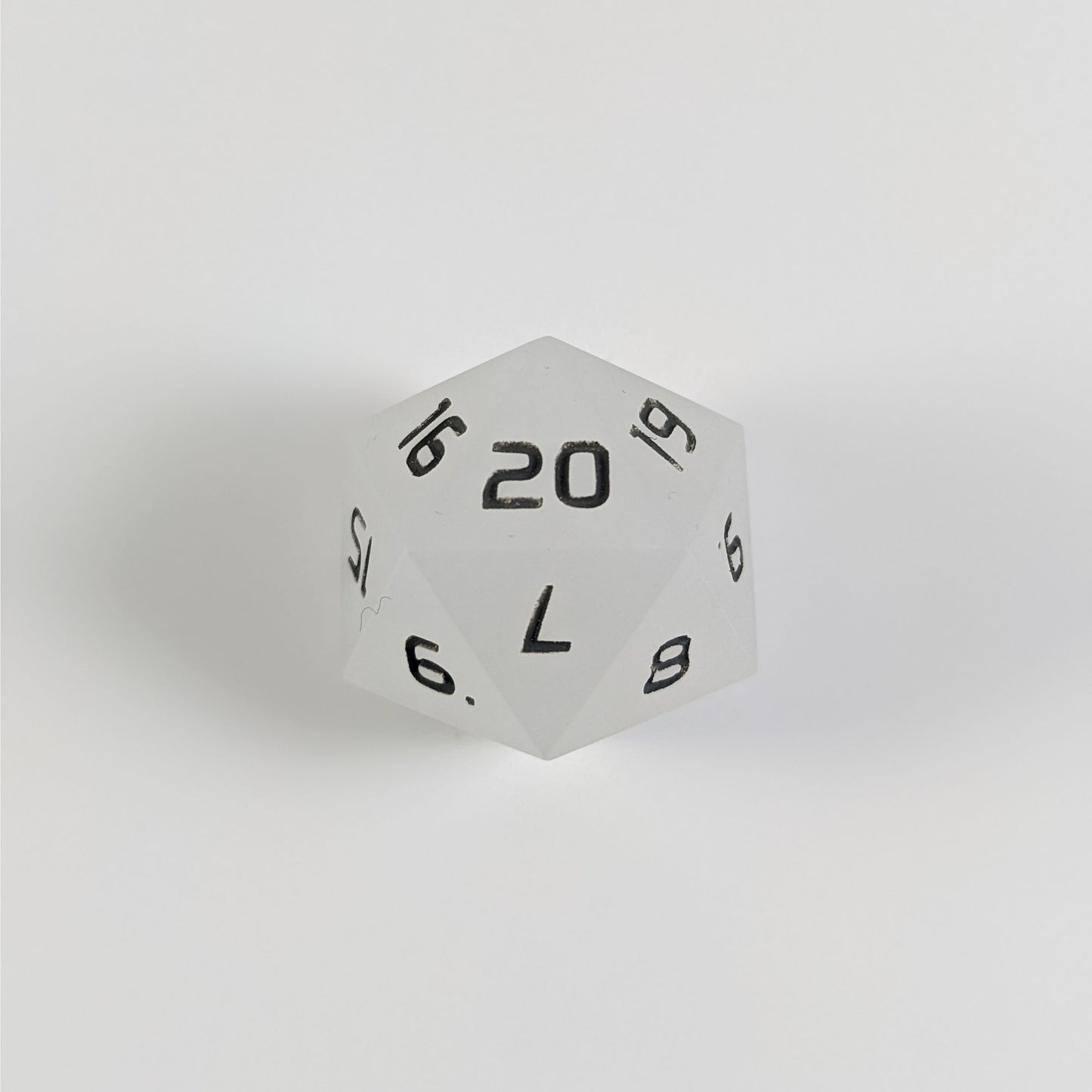 A white spindown d20 with gray numbers and a right spin sits on a white background with the 20 face up.