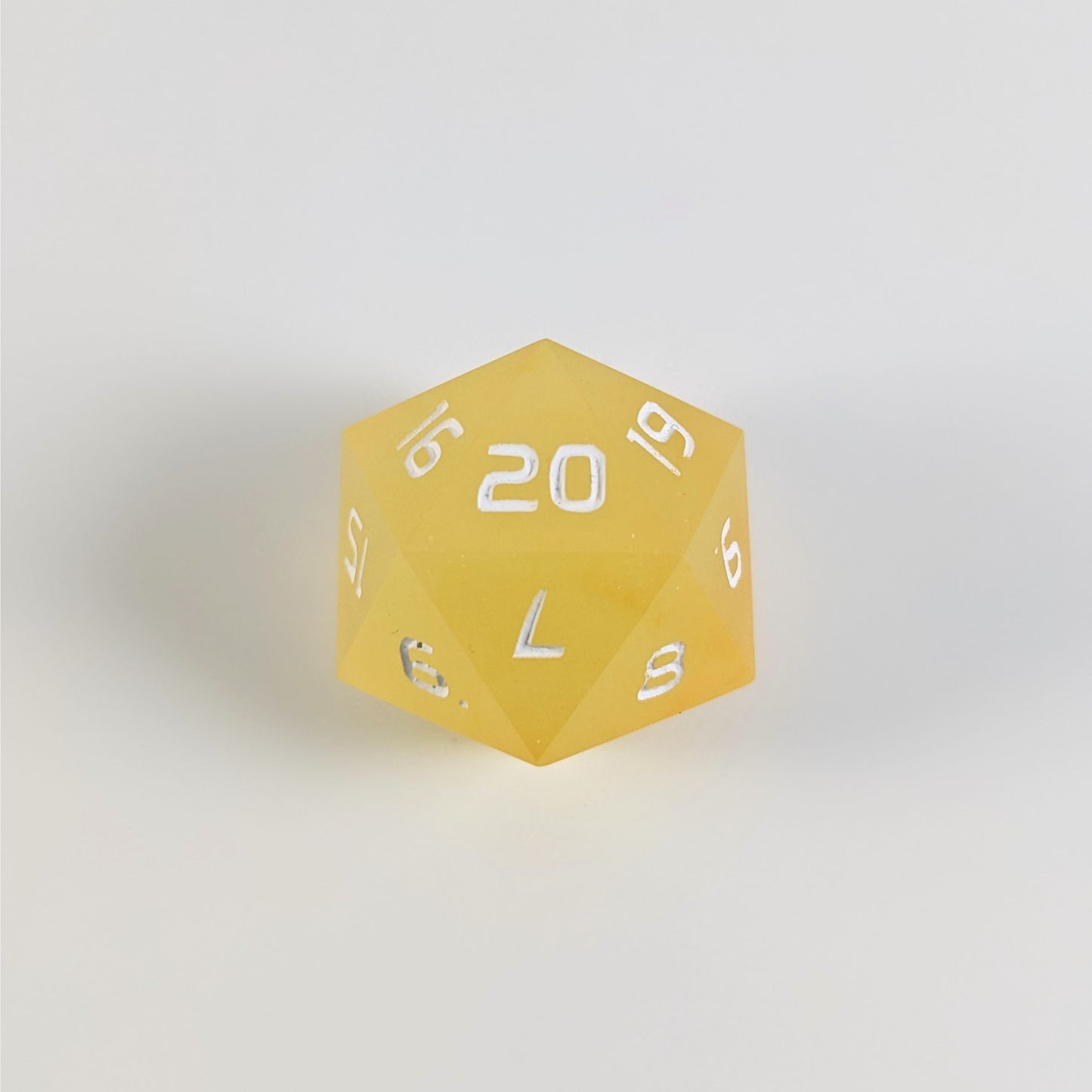 A yellow spindown d20 with white numbers and a right spin sits on a white background with the 20 face up.