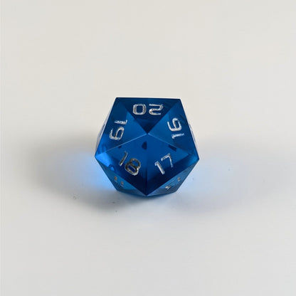 A low angle of a blue spindown d20 with silver numbers and a right spin sits on a white background with the 20 through 16 corner facing the camera showing the spiral of the spin down.