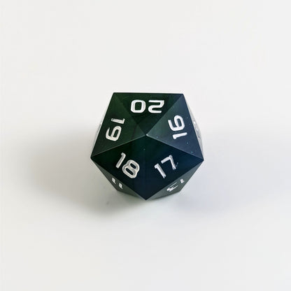 A low angle of a blue and green spindown d20 with white numbers and a right spin sits on a white background with the 20 through 16 corner facing the camera showing the spiral of the spin down.