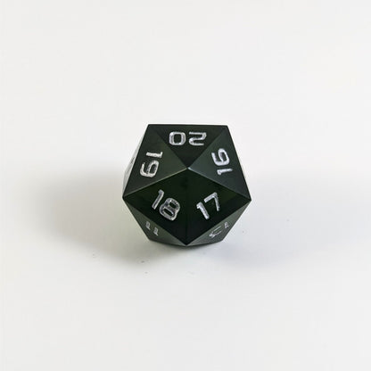 A low angle of a dark green spindown d20 with silver numbers and a right spin sits on a white background with the 20 through 16 corner facing the camera showing the spiral of the spin down.