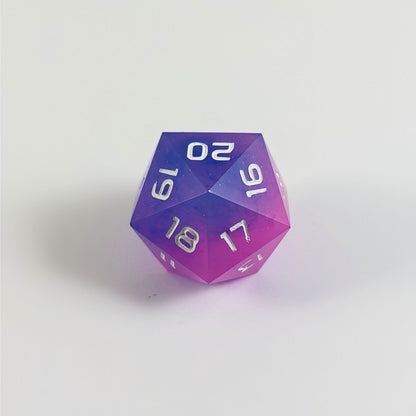 A low angle of a pink and blue spindown d20 with white numbers and a right spin sits on a white background with the 20 through 16 corner facing the camera showing the spiral of the spin down.