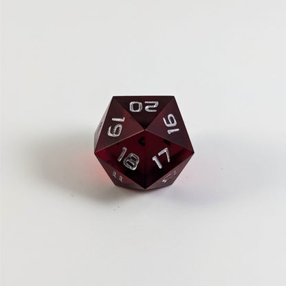 A low angle of a red spindown d20 with silver numbers and a right spin sits on a white background with the 20 through 16 corner facing the camera showing the spiral of the spin down.