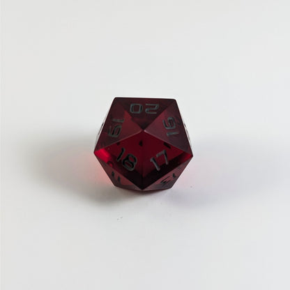 A low angle of a red spindown d20 with gray numbers and a right spin sits on a white background with the 20 through 16 corner facing the camera showing the spiral of the spin down.