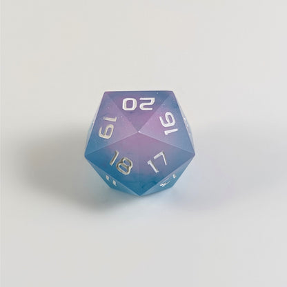 A low angle of an opaque pink and teal spindown d20 with white numbers and a right spin sits on a white background with the 20 through 16 corner facing the camera showing the spiral of the spin down.