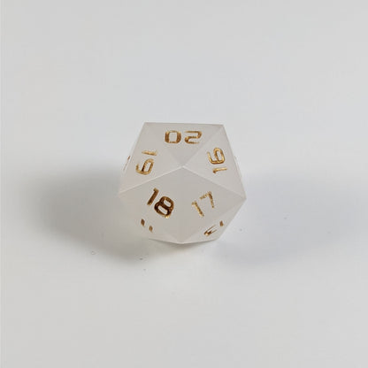A low angle of a white spindown d20 with gold numbers and a right spin sits on a white background with the 20 through 16 corner facing the camera showing the spiral of the spin down.