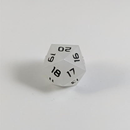 A low angle of a white spindown d20 with gray numbers and a right spin sits on a white background with the 20 through 16 corner facing the camera showing the spiral of the spin down.