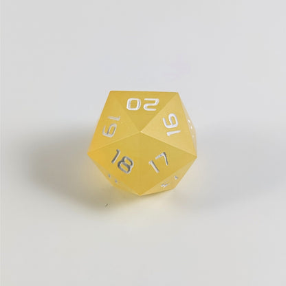 A low angle of a yellow spindown d20 with white numbers and a right spin sits on a white background with the 20 through 16 corner facing the camera showing the spiral of the spin down.