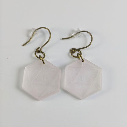 A pair of pale pink and white dangly, flat d20 earrings with gold color titanium and niobium hardware and bell shaped rubber backs on a white background. The earring on the left has a 20 on it and the earring on the right has a 1 on it, both in a sci-fi style font.