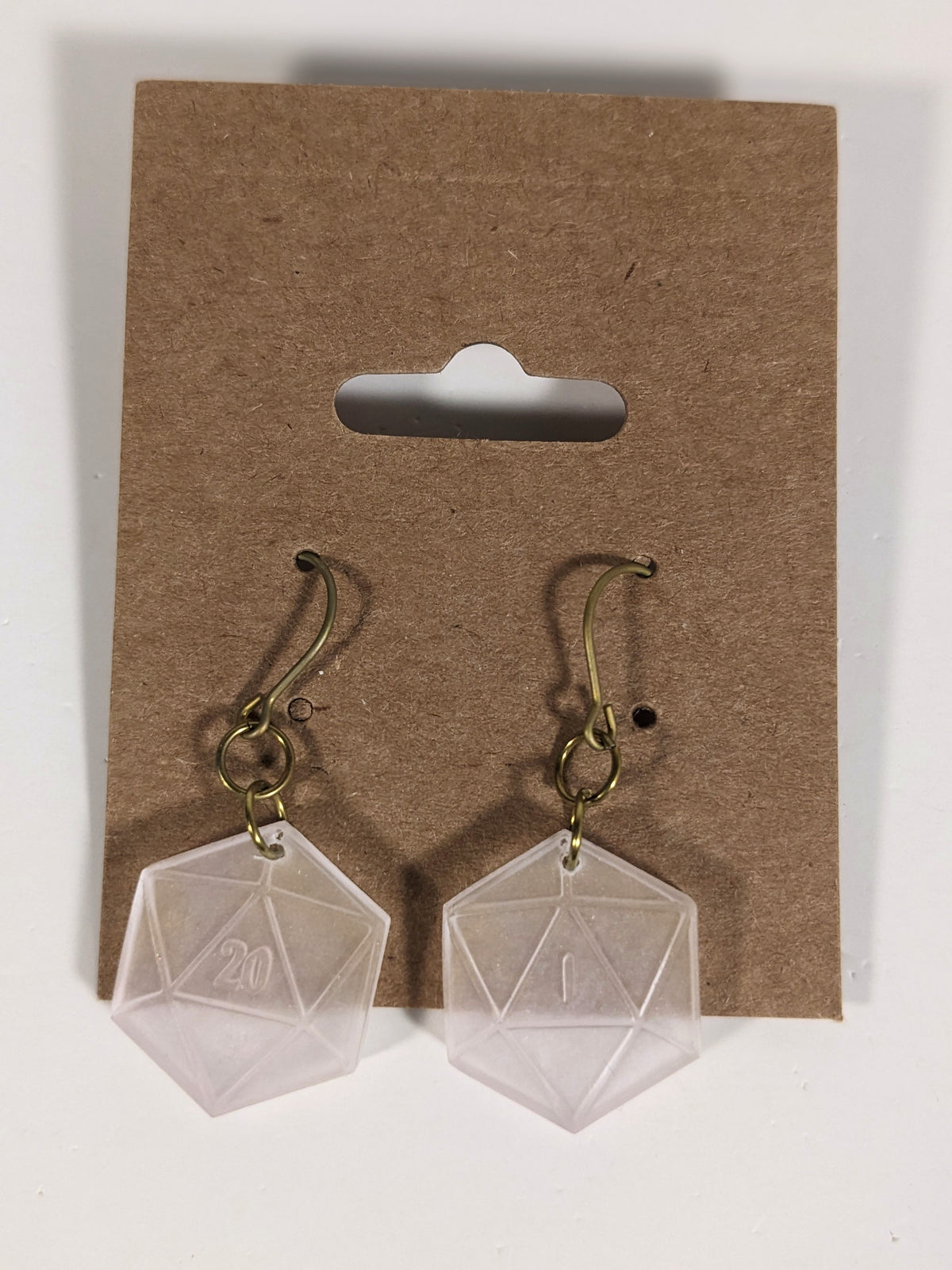 A pair of pale pink and white dangly, flat d20 earrings with gold color titanium and niobium hardware on a kraft earring card on a white background. The earring on the left has a 20 on it and the earring on the right has a 1 on it, both in a fantasy style font.
