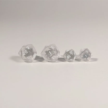 Two pairs of handmade d20 earrings with titanium hardware that are faded pink and translucent white with white numbers on a white background sit in a line with the larger pair on the left and the smaller pair on the right. The earrings on the left of each pair centers the 20 face and the earrings on the right of each pair centers the 1 face.