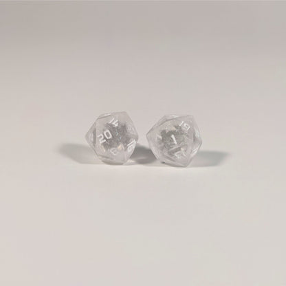 A single pair of the larger size handmade d20 earrings with titanium hardware that are glittery clear with pink flakies with white numbers on a white background. The earring on the left centers the 20 face and the earring on the right centers the 1 face.