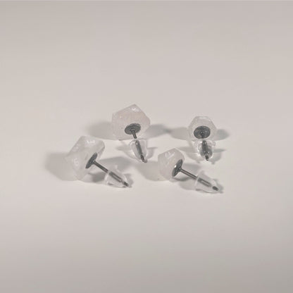 Two pairs of handmade d20 earrings that are faded pink and translucent white with white numbers turned to show the titanium hardware and bell shaped rubber backs.