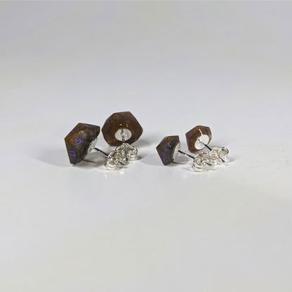 Two pairs of handmade d20 earrings that are dark gold with purple numbers turned to show the sterling silver hardware and butterfly backs.