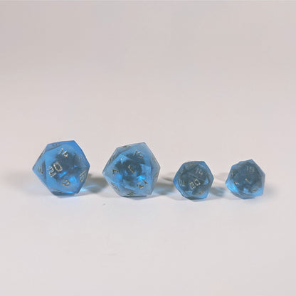 Two pairs of handmade d20 earrings with titanium hardware that are sapphire blue with bronze numbers on a white background sit in a line with the larger pair on the left and the smaller pair on the right. The earrings on the left of each pair centers the 20 face and the earrings on the right of each pair centers the 1 face.